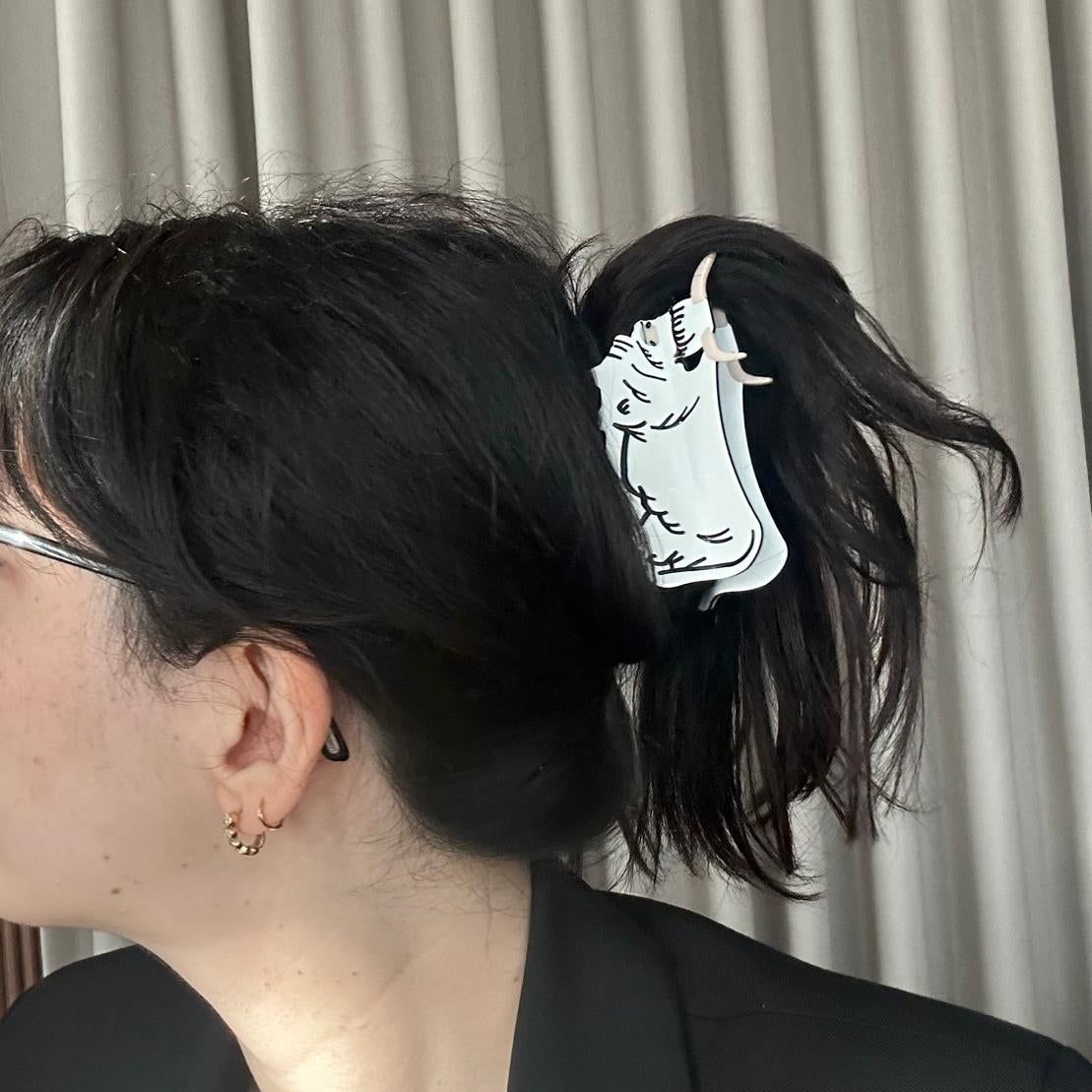 Person with a hair clip featuring a white design against a neutral background
